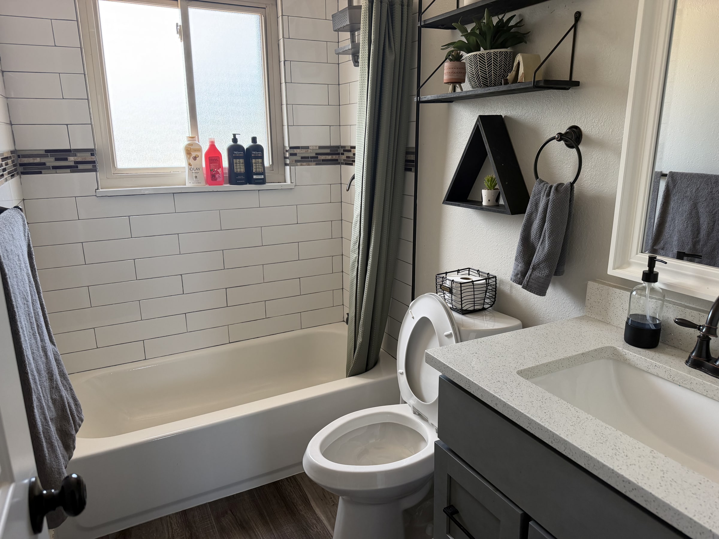 Bright bathroom with clean tub, vanity, toilet, and tile floor