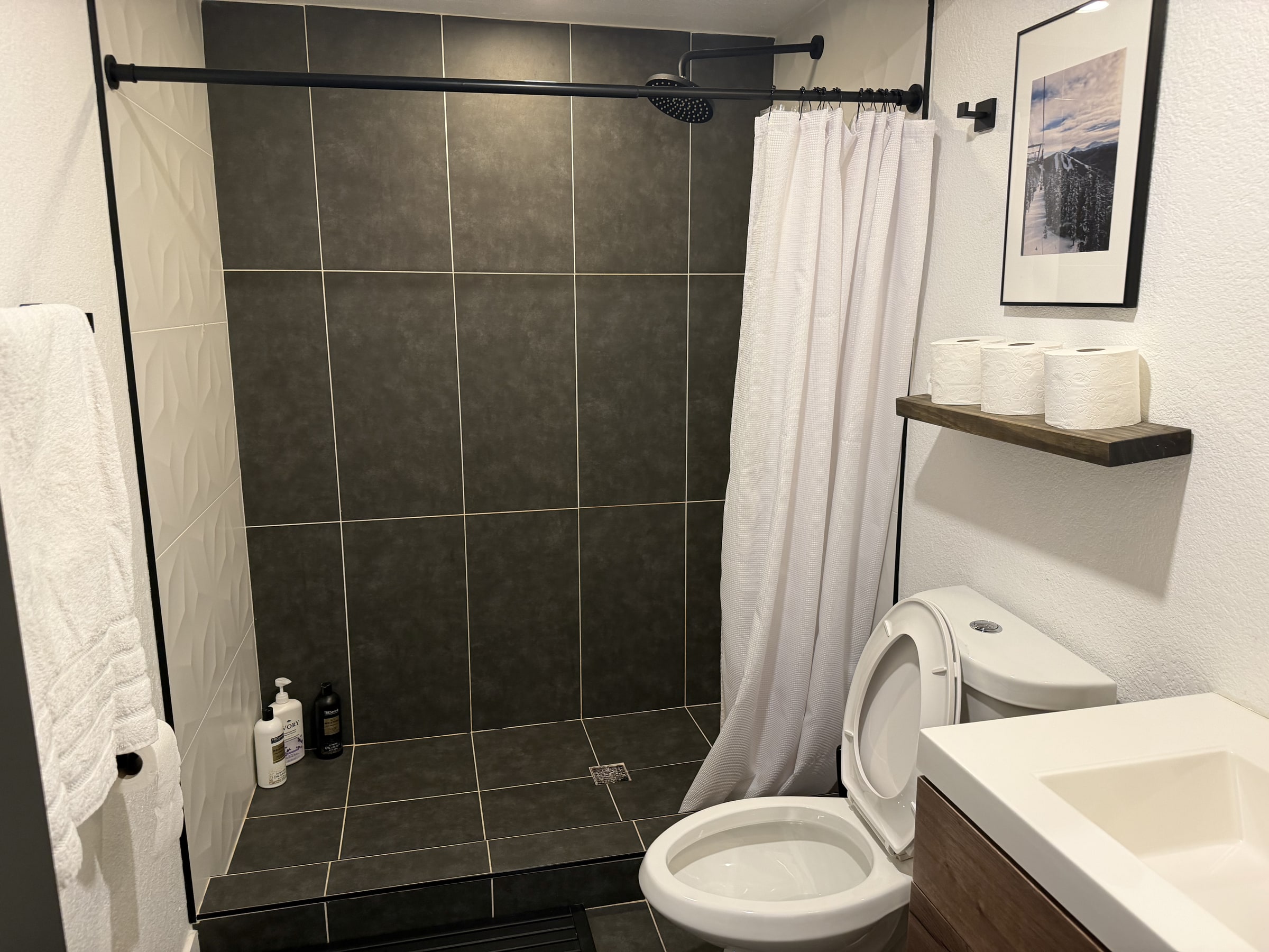 Clean bathroom with charcoal shower tile and white vanity