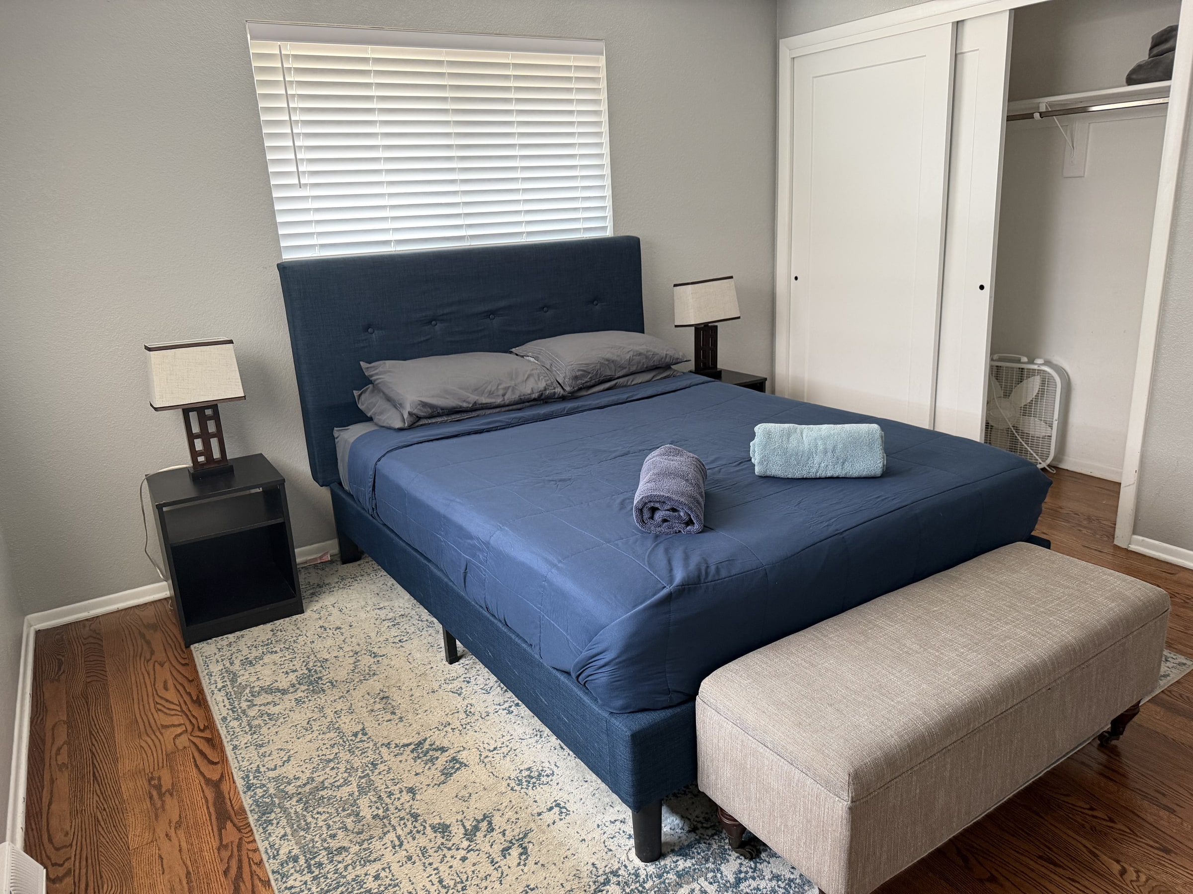 Bedroom with navy bedding, clean floors, and folded towels