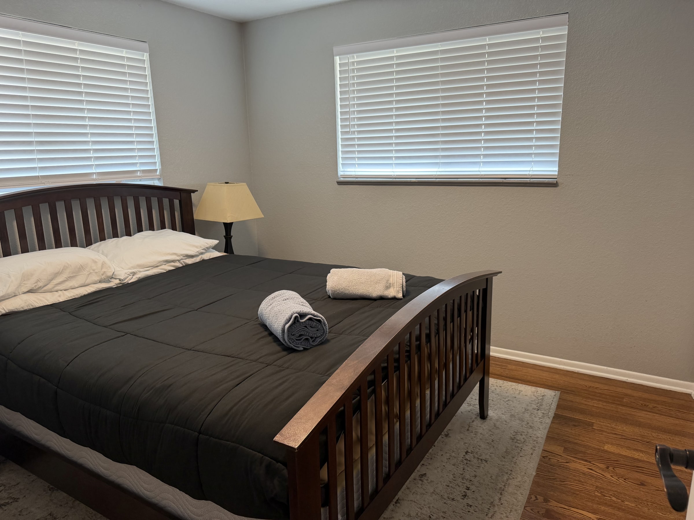 Bedroom with dark wood bed frame and neatly folded towel