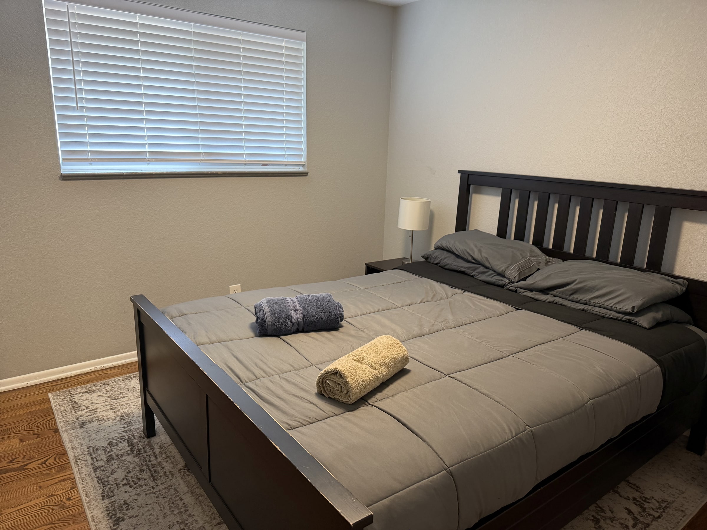 Bedroom with clean dark bedding and bedside lamp