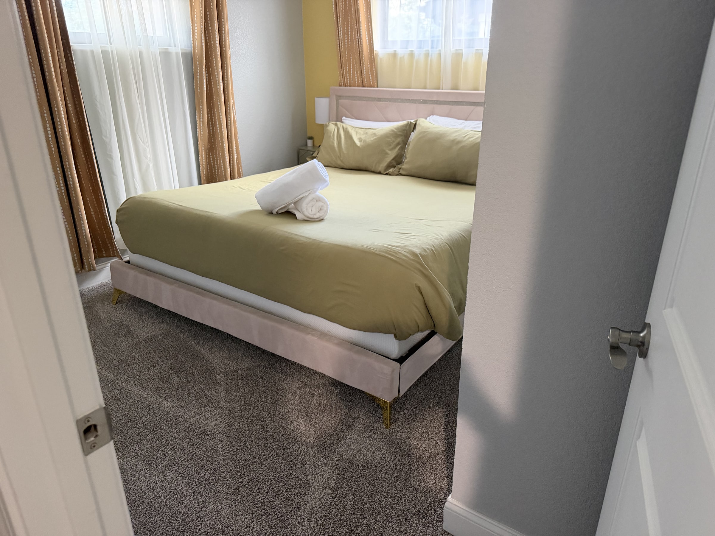 Small bedroom with green bedding and clean carpet
