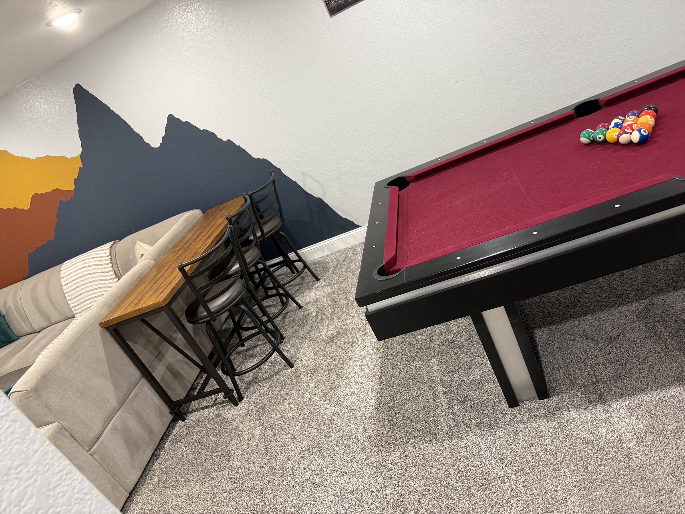 Game area with pool table, seating, and colorful wall art