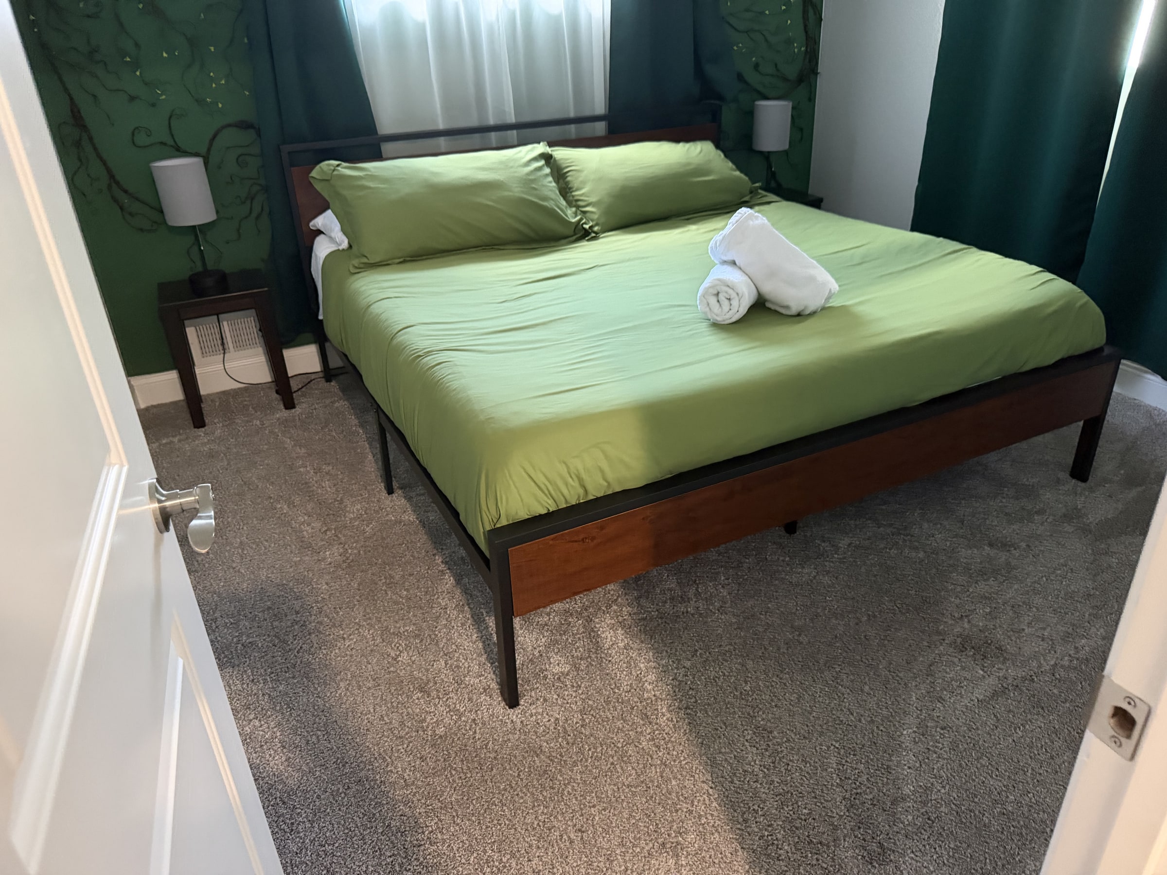 Bedroom with green bedding and neatly folded towel