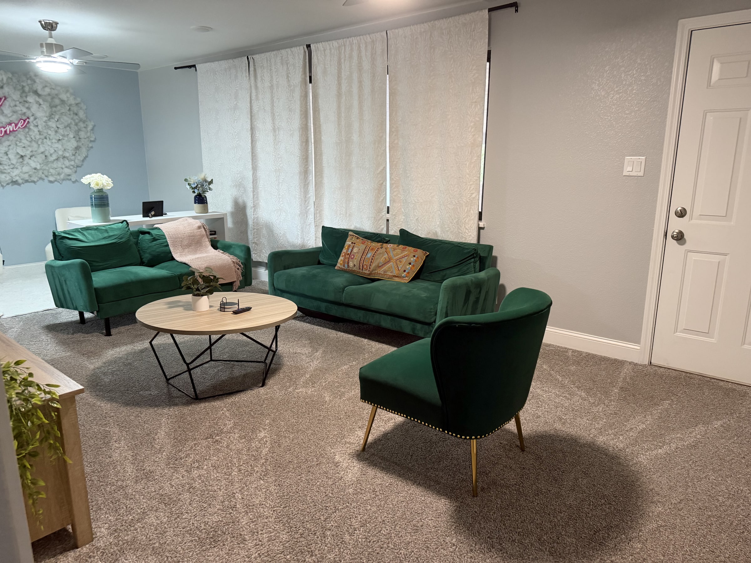 Living room with green chairs, sofa, and clean carpet