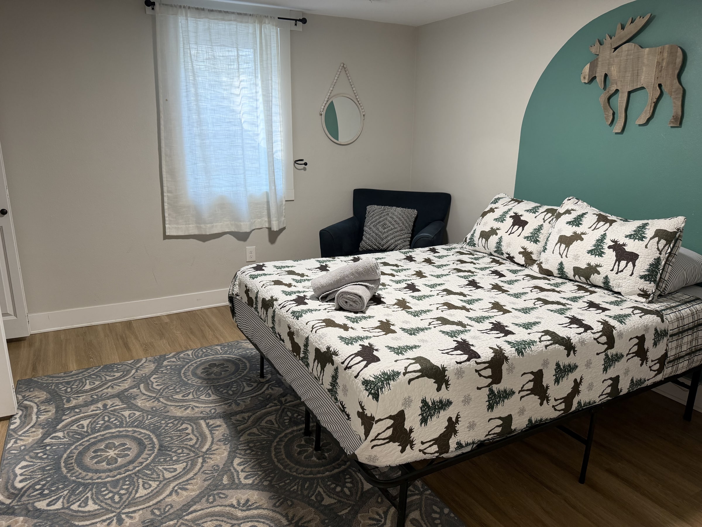 Bedroom with patterned bedding, teal wall accent, and tidy floor