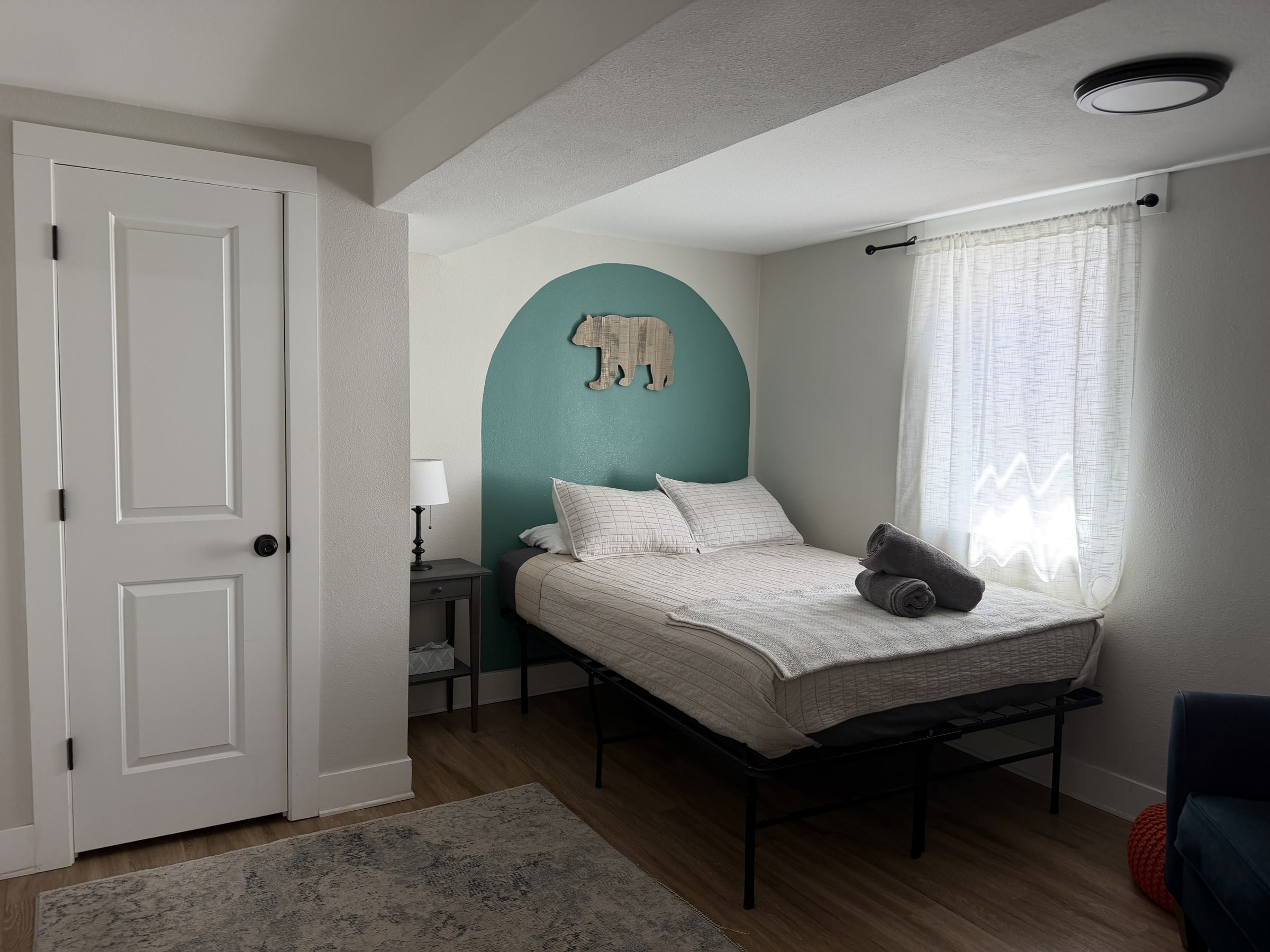 Bedroom with arched teal headboard and clean staging