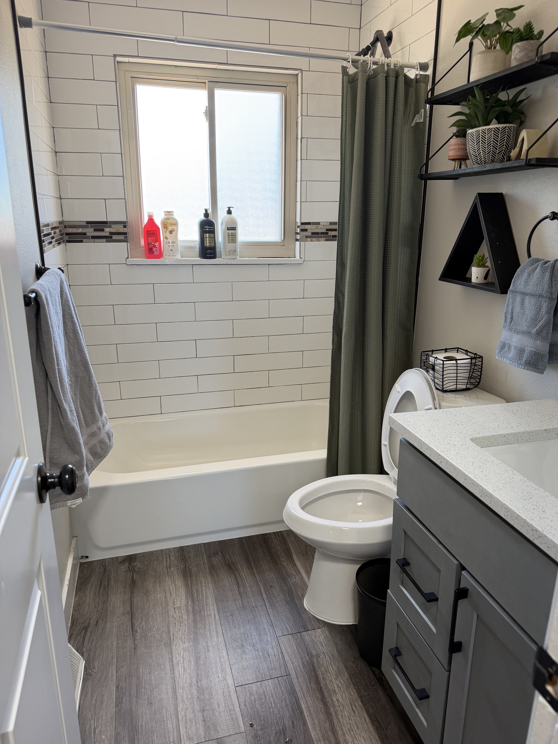 Portrait view of a clean bathroom tub and white tile wall