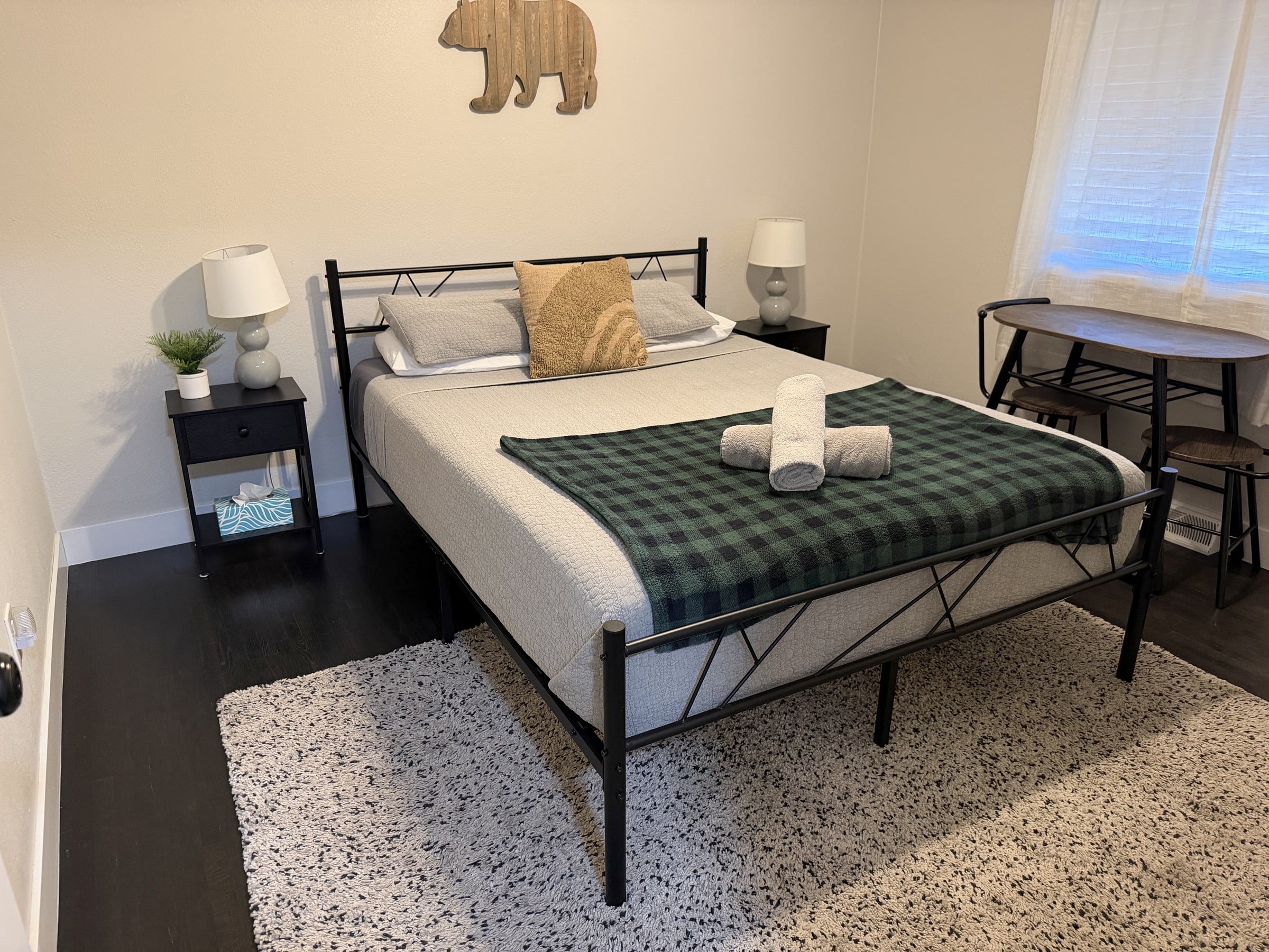 Bedroom with green bedding, gold pillows, and folded towels